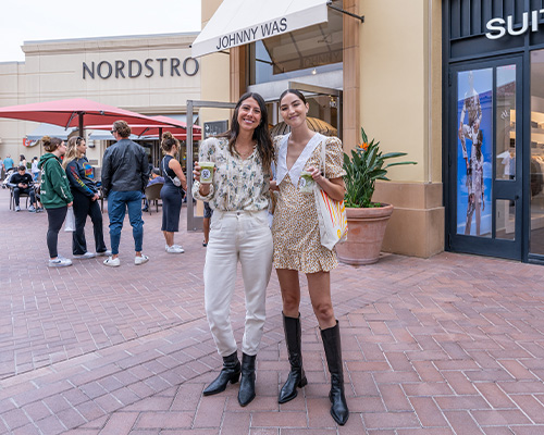 Two girls posing in front of Johnny Was storefront